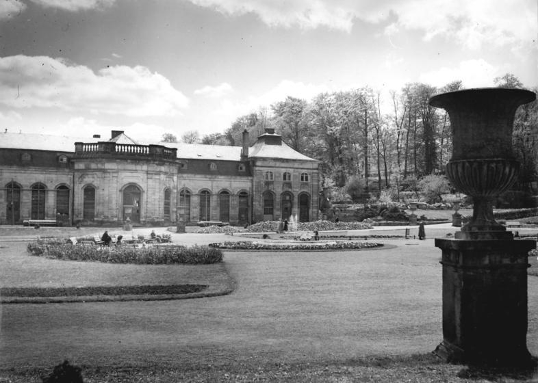 1956 begannen die Sanierung des „Lorbeerhauses“ und sein Ausbau als „Orangerie-Konzertcafé“. Diese Aufnahme zeigt nicht nur sehr deutlich die seit dem Krieg vernagelten Fenster des Gebäudes, sondern auch sehr deutlich den bereits beräumten Platz des abgebrochenen südlichen Treibhauses. Bis heute ist es unverständlich, wie rabiat die Gothaer Stadtväter mit der einmaligen historischen Bausubstanz umgingen und vieles unwiederbringlich zerstörten. (Foto: Bundesarchiv)