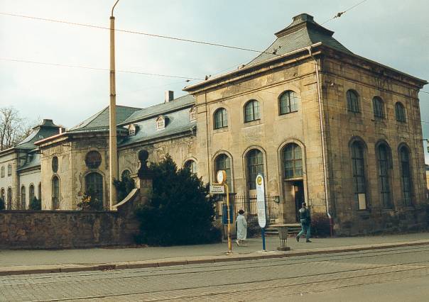 Blick von Südosten auf die Rückseite und den Ostpavillon des „Lorbeerhauses“. Deutlich sichtbar sind bereits die Schäden an der Fassade sowie einige mit Holzplatten verschlossene (weil zerstörte) Fenster. Interessantes Detail: Die Straßenbahnhaltestelle Orangerie weist sowohl noch das alte, DDR-typische Haltestellenschild als auch bereits ein moderneres Schild auf. (Foto: MRV)