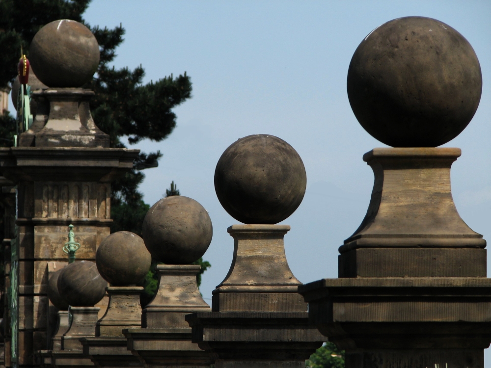 Ursprünglich wurden die Pfeiler des Portals und des Zaunes der Orangerie von steinernen Granatäpfeln gekrönt. Nach dem Tode Herzog Friedrichs III. im Jahre 1772 ließ sein Sohn Ernst II. diese jedoch entfernen und durch die schlichteren Kugeln ersetzen, die heute noch zu sehen sind. (Foto: Cramer)